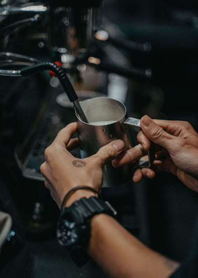 preparing drinking chocolate with steam pipe espresso machine in pitcher