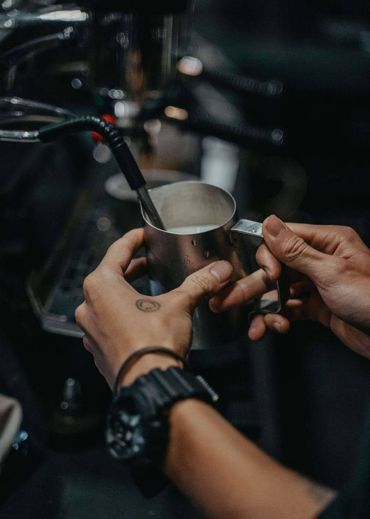 preparing drinking chocolate with steam pipe espresso machine in pitcher